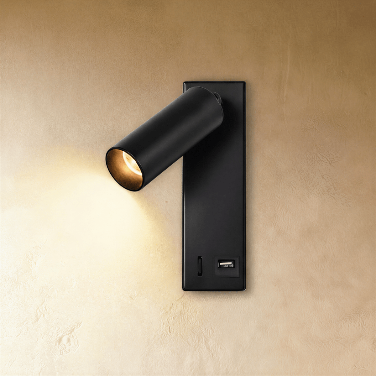 Clérachic matt black wall reading light glowing warm, with a USB socket at the base of its slim rectangular backplate.