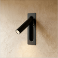 Clérachic slim wall-mounted reading light in matt black, its round-headed spotlight arm swung out from the plate.