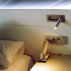 Clérachic recessed reading light above a bedside, with a socket panel and desk lamp below.