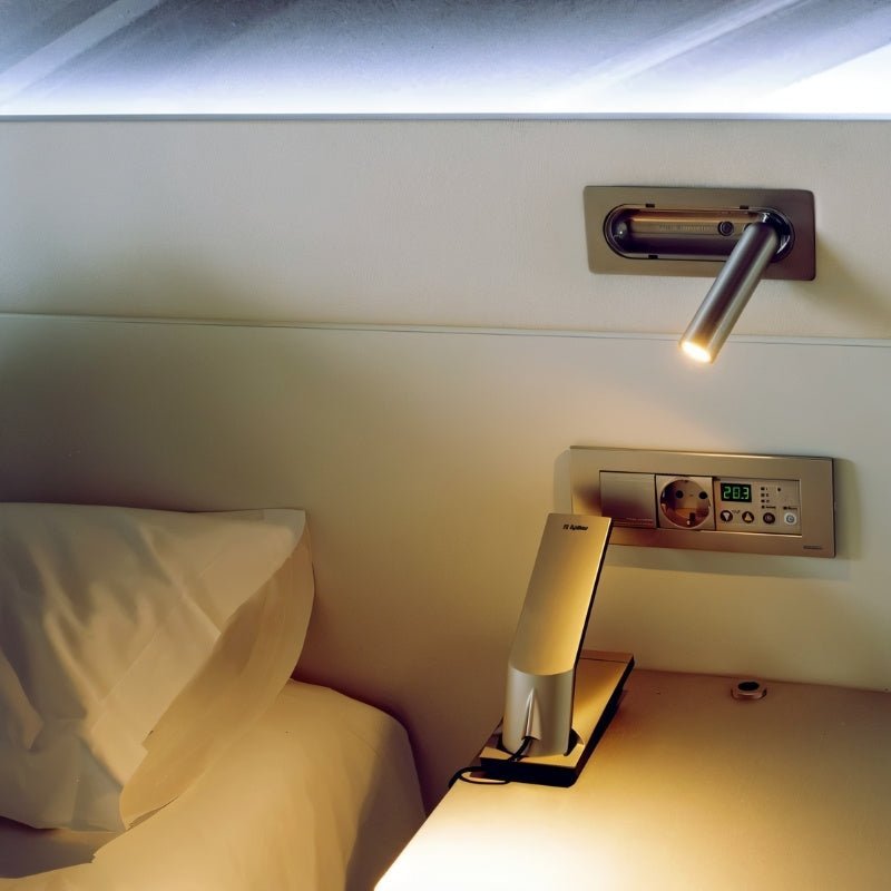Clérachic recessed reading light above a bedside, with a socket panel and desk lamp below.
