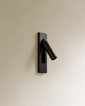 Clérachic black recessed wall reading lamp with a slim cylindrical head swung out from a rectangular plate on a cream wall.