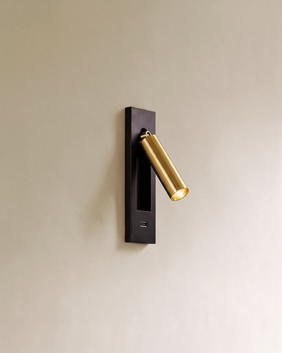 Clérachic black and gold wall reading lamp with a USB-C port in the lower plate and a brushed gold head angled outward.
