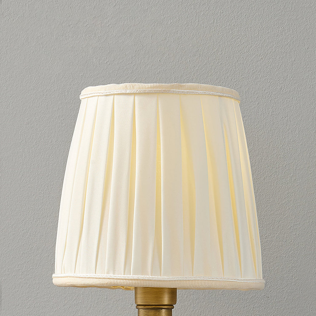 Close view of the beige pleated fabric shade of this Clérachic wall light, with a trimmed top and bottom edge.