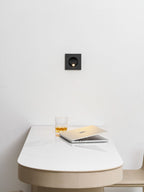 Black Clérachic recessed wall light above a curved cream desk top, with a glass of whisky and a laptop beneath.
