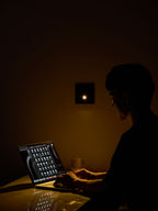 Someone types on a laptop at a desk in a dark room, lit only by this Clérachic recessed wall light on the wall behind.
