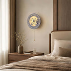 Round Clérachic wall light with a floral blue and white shade, hung over a wood bedside table with a vase of twigs and a glass of water.