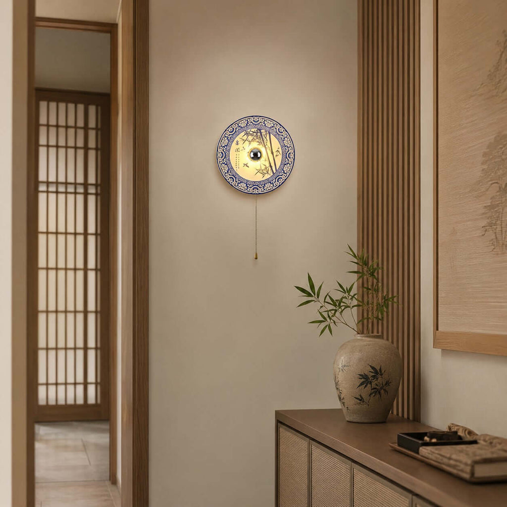 A Clérachic wall light beside a sliding lattice door, its pull chain hanging above a wood console with a patterned jar.
