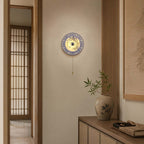 A Clérachic wall light beside a sliding lattice door, its pull chain hanging above a wood console with a patterned jar.