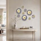 A group of Clérachic porcelain wall lights in several sizes and patterns, arranged as a cluster above a console table with a vase of blossom.