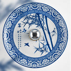 Close view of the blue bamboo and bird design on this Clérachic wall light's porcelain shade, with its mirrored centre boss.