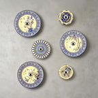 Six Clérachic wall lights, from small to large, in floral, bamboo and petal patterns on a grey wall.