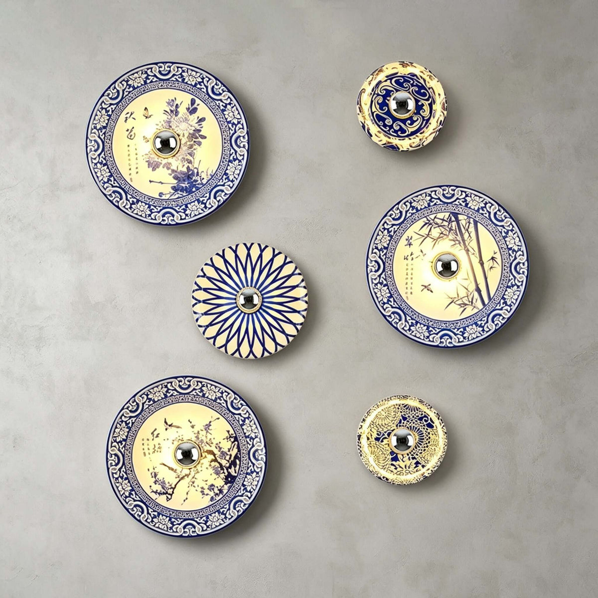 Six Clérachic wall lights, from small to large, in floral, bamboo and petal patterns on a grey wall.