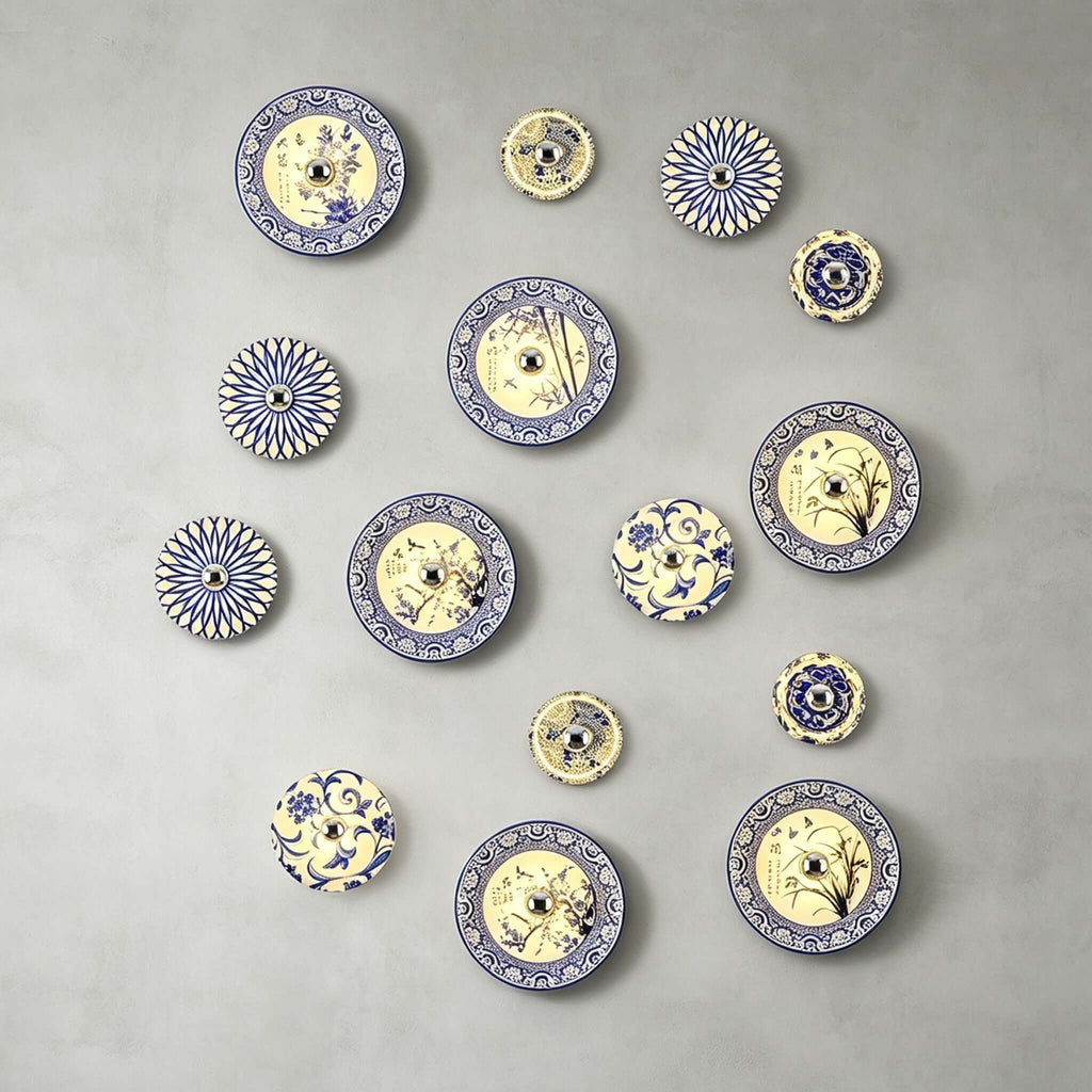 A wide cluster of many Clérachic wall lights in many sizes and blue and white patterns on a grey wall.