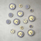 A wide cluster of many Clérachic wall lights in many sizes and blue and white patterns on a grey wall.