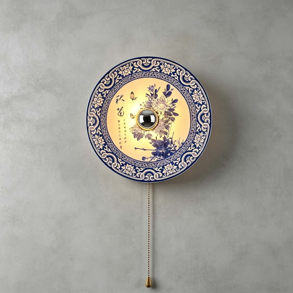 Clérachic wall light with a purple-blue chrysanthemum design inside a blue lattice border, lit, on a grey concrete wall.
