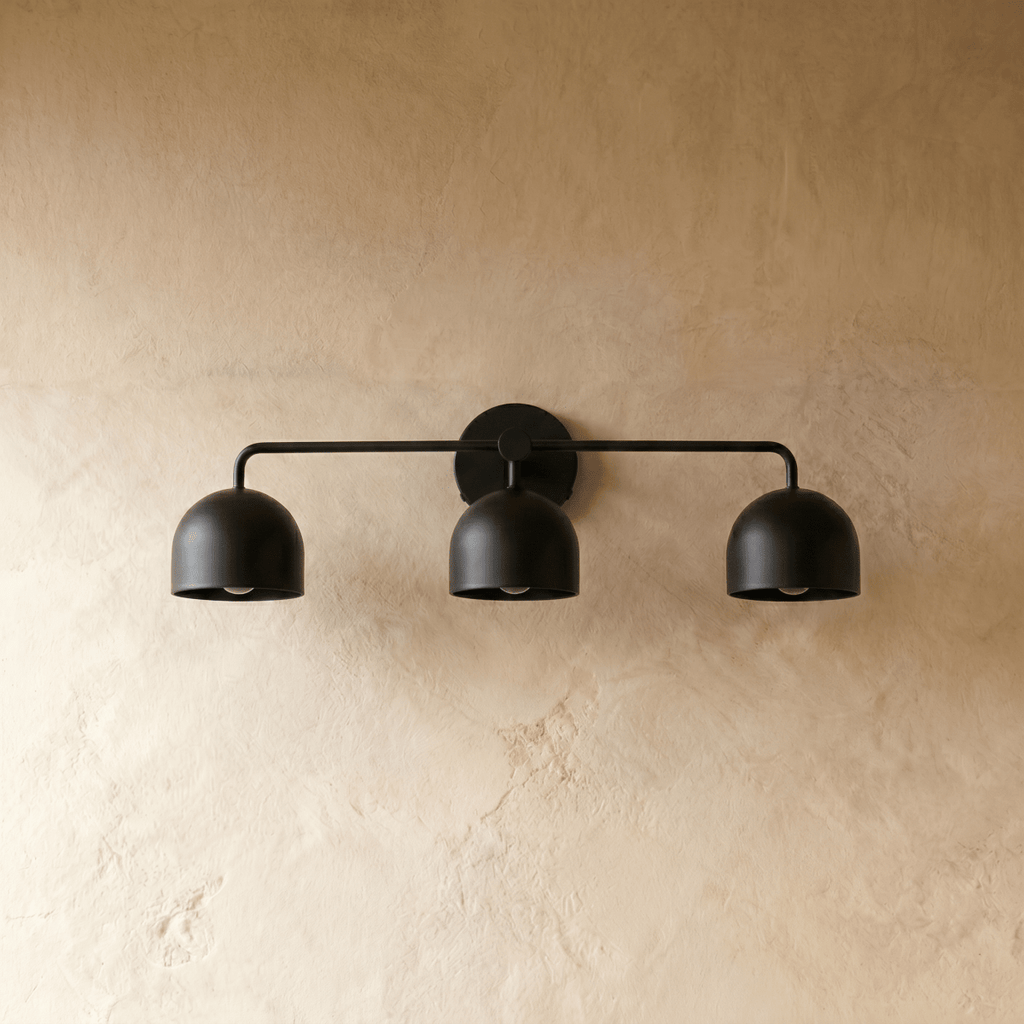 Clérachic three-light bar sconce in matte black, shown from a slightly closer studio angle on a plaster wall.
