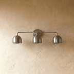 Clérachic three-light bar sconce in chrome, shown from a slightly closer studio angle on a plaster wall.