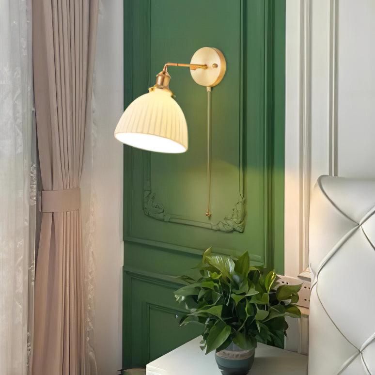 This Clérachic wall light hangs beside a dark green panelled door and cream curtain, a potted plant on a white table below.
