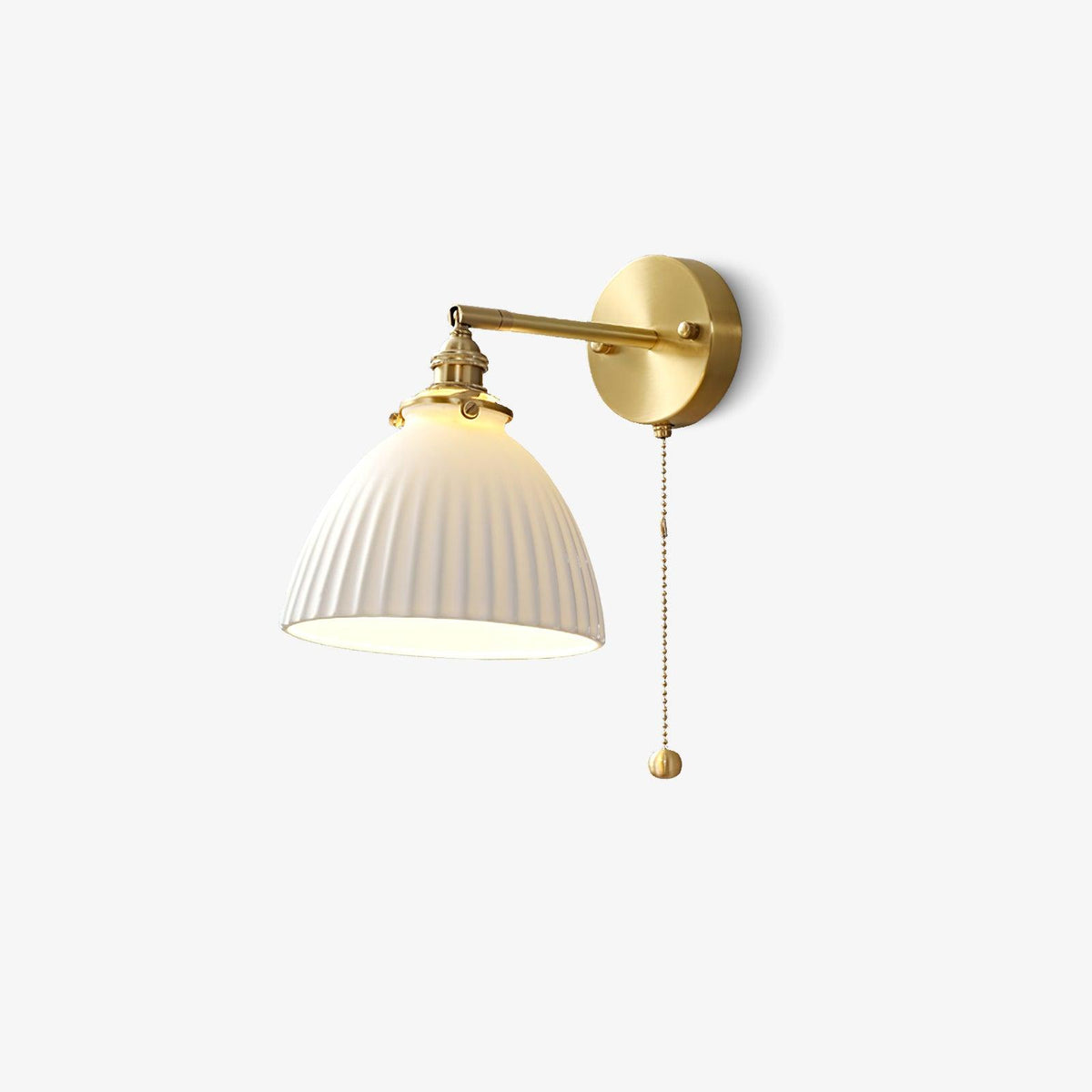 This Clérachic wall light on a plain off-white backdrop, its brass arm, pleated white shade and bead pull chain clear.