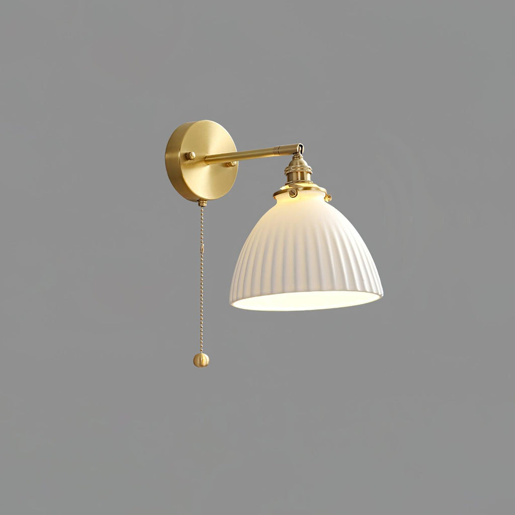 Brass-armed Clérachic wall light with a pleated white ceramic shade and a long pull chain, shown against mid-grey.