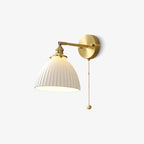 A Clérachic wall light shown on white, with a brass swing arm, round backplate and a pleated white shade.