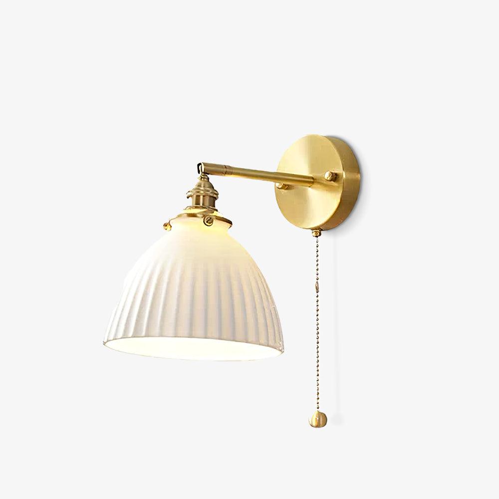 Slightly angled view of the Clérachic wall light, its pleated white ceramic shade hung on a brass arm on a white background.