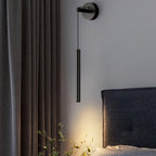 Close to a charcoal curtain and a woven headboard, a black Clérachic wall light hangs from its round backplate.