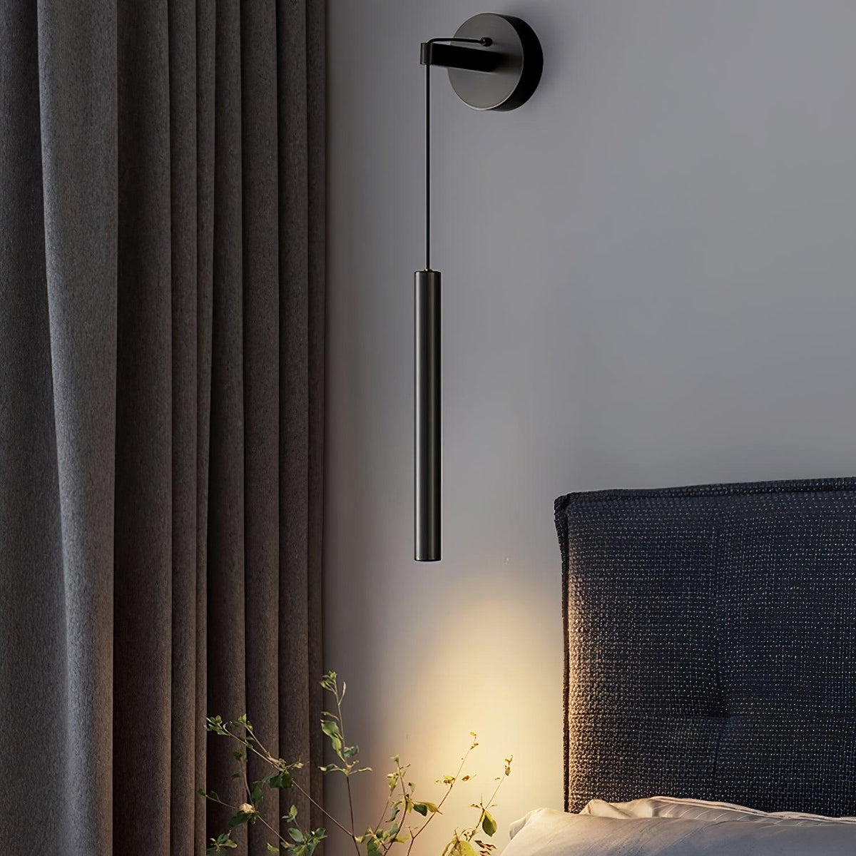 Close to a charcoal curtain and a woven headboard, a black Clérachic wall light hangs from its round backplate.