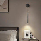 Black wall light hanging above a bedside table with a framed photo and toiletries, its light pooling on the wall, a Clérachic wall light.