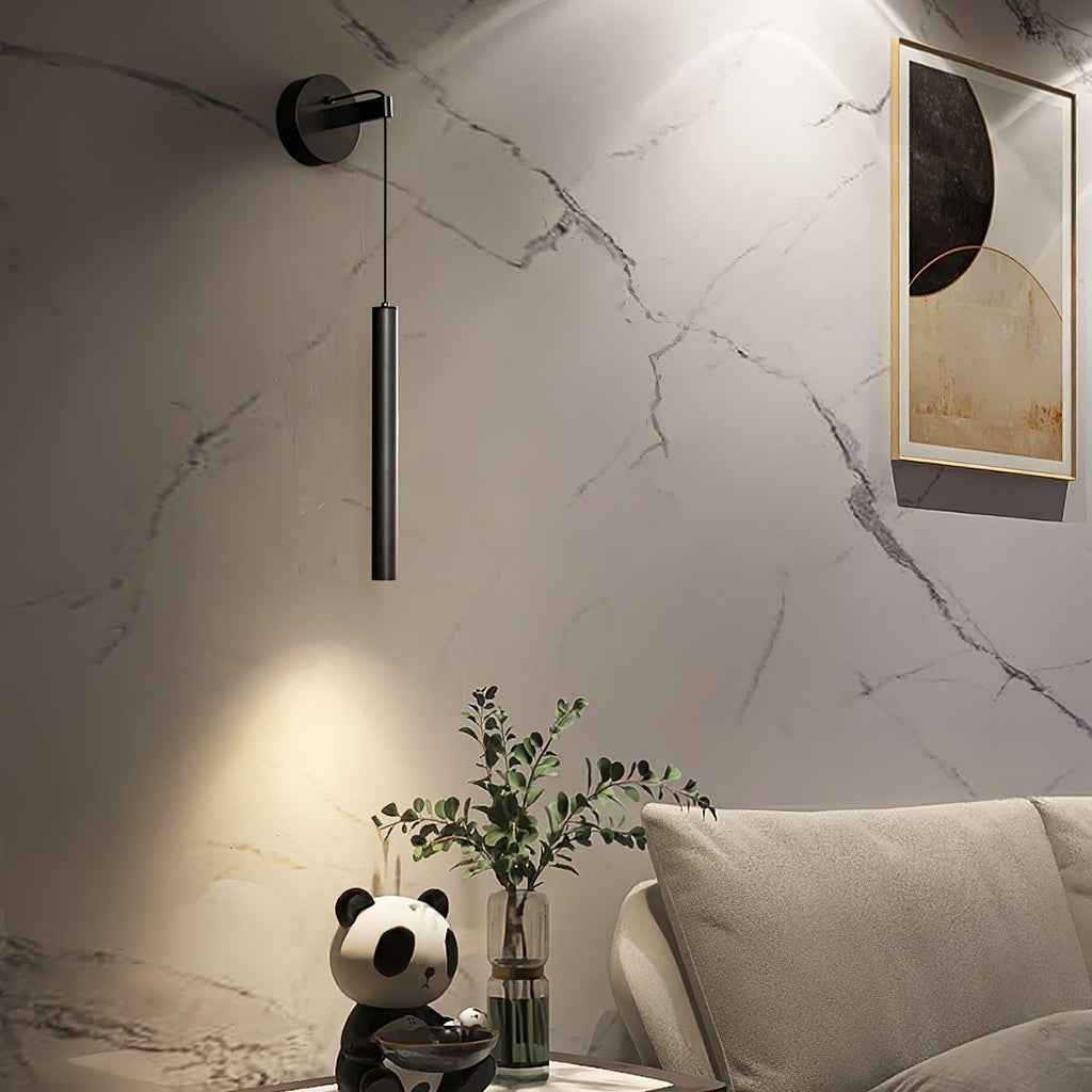 Black tube wall light on a white marble-effect wall above a sofa with a panda figure and green plant, from Clérachic.