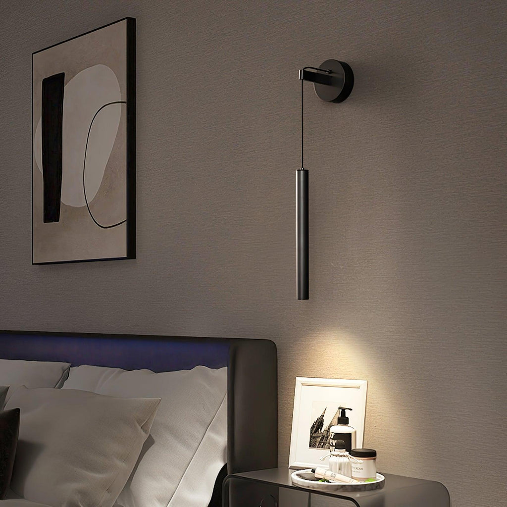 Black tube wall light beside an abstract framed print above a bed and glass bedside table, from Clérachic.