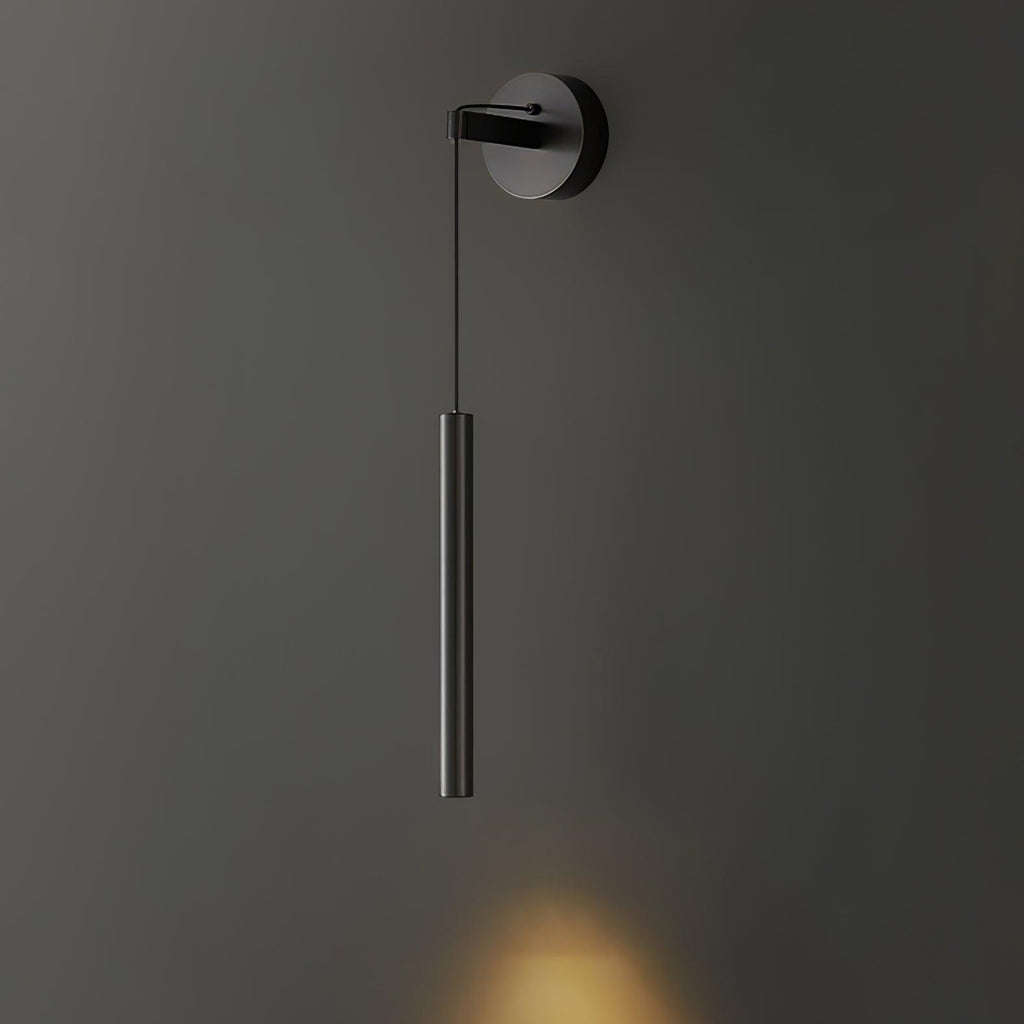 Black tube wall light on a dark olive-grey wall, with a small warm patch of light at the bottom edge, a Clérachic wall light.