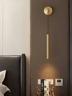 Brass wall light on a dark panelled wall beside a cream wall and a leather headboard, a bright pool of light below, from Clérachic.