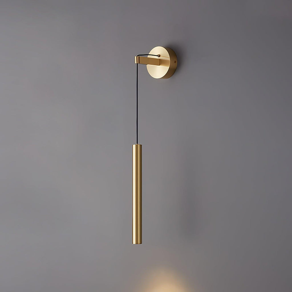 Brass tube wall light on a mid-grey wall, lit at the bottom with a soft warm glow, a Clérachic wall light.