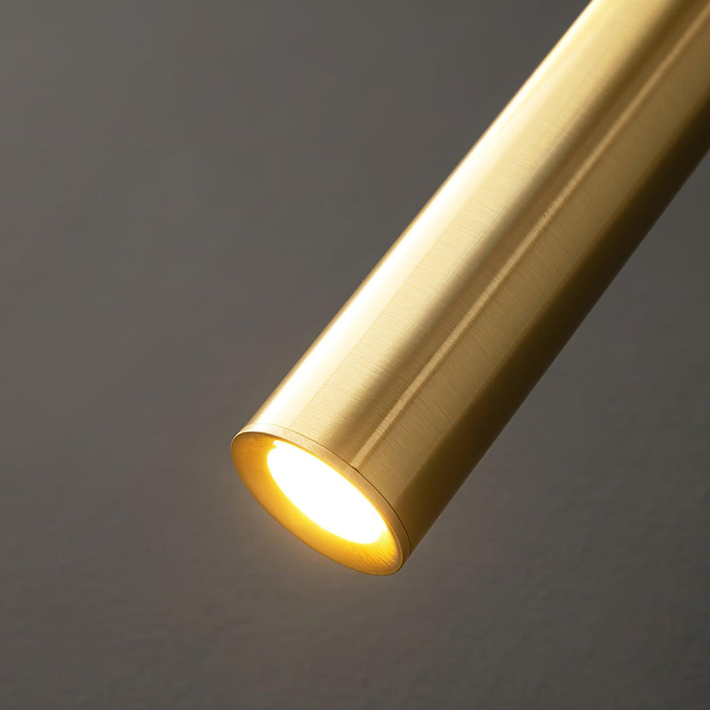 Close view of the lit end of the brushed brass tube, with the LED glowing inside, on this Clérachic wall light.