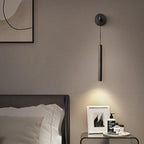 Black wall light over a glass bedside table with a framed photo and toiletries, light pooling on the wall, a Clérachic wall light.