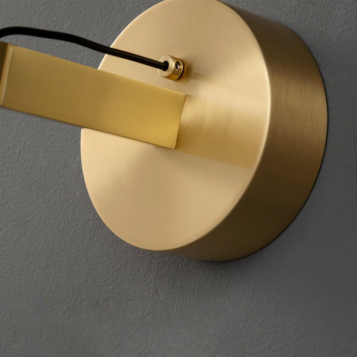 Close view of the brushed brass backplate and the cord entry on this Clérachic wall light.
