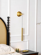 Brass wall light between white wall panels, with an arched headboard and a black carved bedpost beside it, a Clérachic wall light.