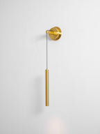 Brass wall light on a pale grey wall, with a faint glow of light below the tube, from Clérachic.