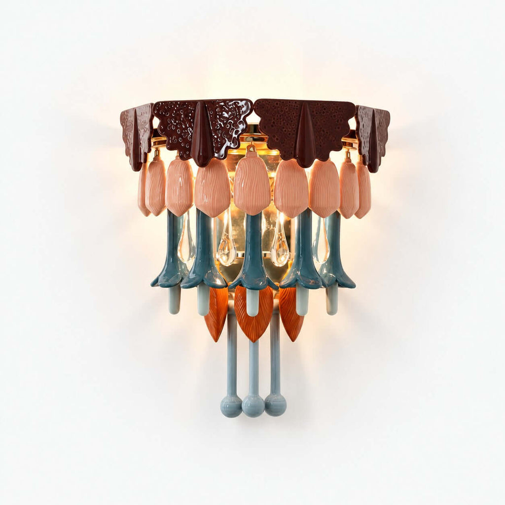 This Clérachic wall sconce on a white background, with a burgundy scalloped top, pink ceramic petals, teal drops and clear glass teardrops.