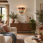 Fluted sideboard below a Clérachic wall sconce, with olive branches, a terracotta vase and a cream sofa draped in a blue throw.