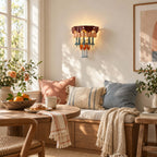 Clérachic wall sconce above a window-side bench with striped and blue cushions, a bowl of oranges and a knitted throw.