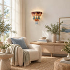 Soft daylight room with a Clérachic wall sconce above a cream armchair with a blue cushion, a low bench and a seascape print.
