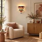 Clérachic wall sconce glowing near a sheer curtain, with a boucle armchair, a pink-blossom vase and a pale wood sideboard.