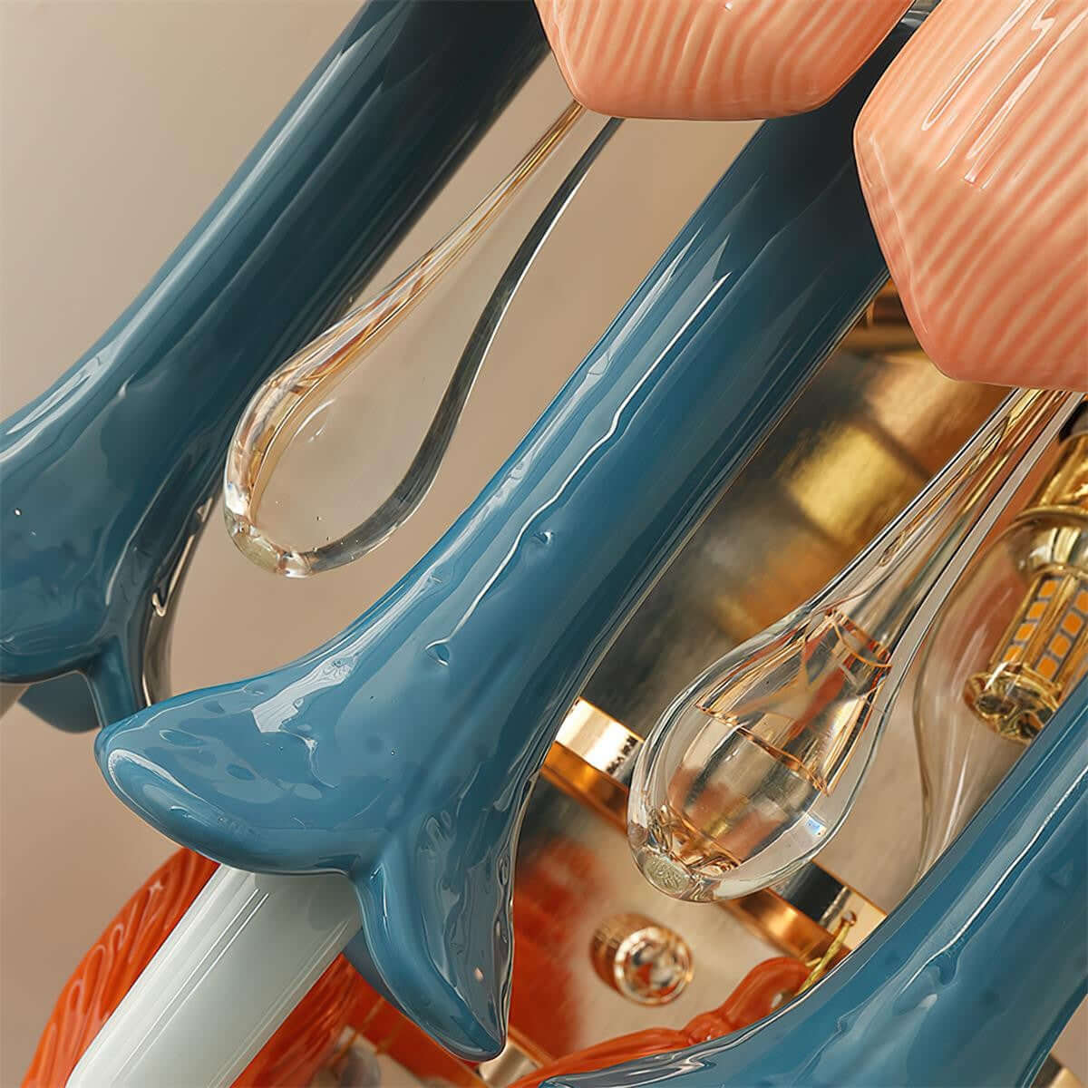 Close view of this Clérachic sconce's glossy blue ceramic stems, clear glass drops and pink petals around the lit gold interior.