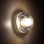 In a dark room, this Clérachic wall lamp glows warm, the bubbled glass dome throwing a soft pool of light across the wall.