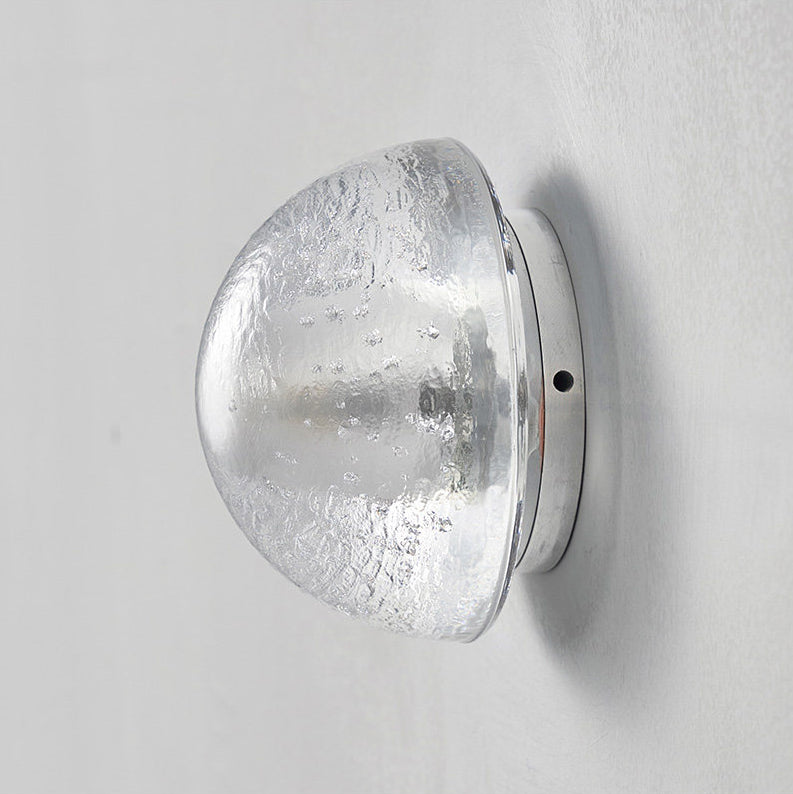 Unlit, the clear glass dome of this Clérachic wall lamp shows its rippled, textured surface and a small screw on the backplate.