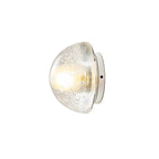 This Clérachic wall lamp on a plain white backdrop, a lit dome of clear bubbled glass on a small round chrome base.