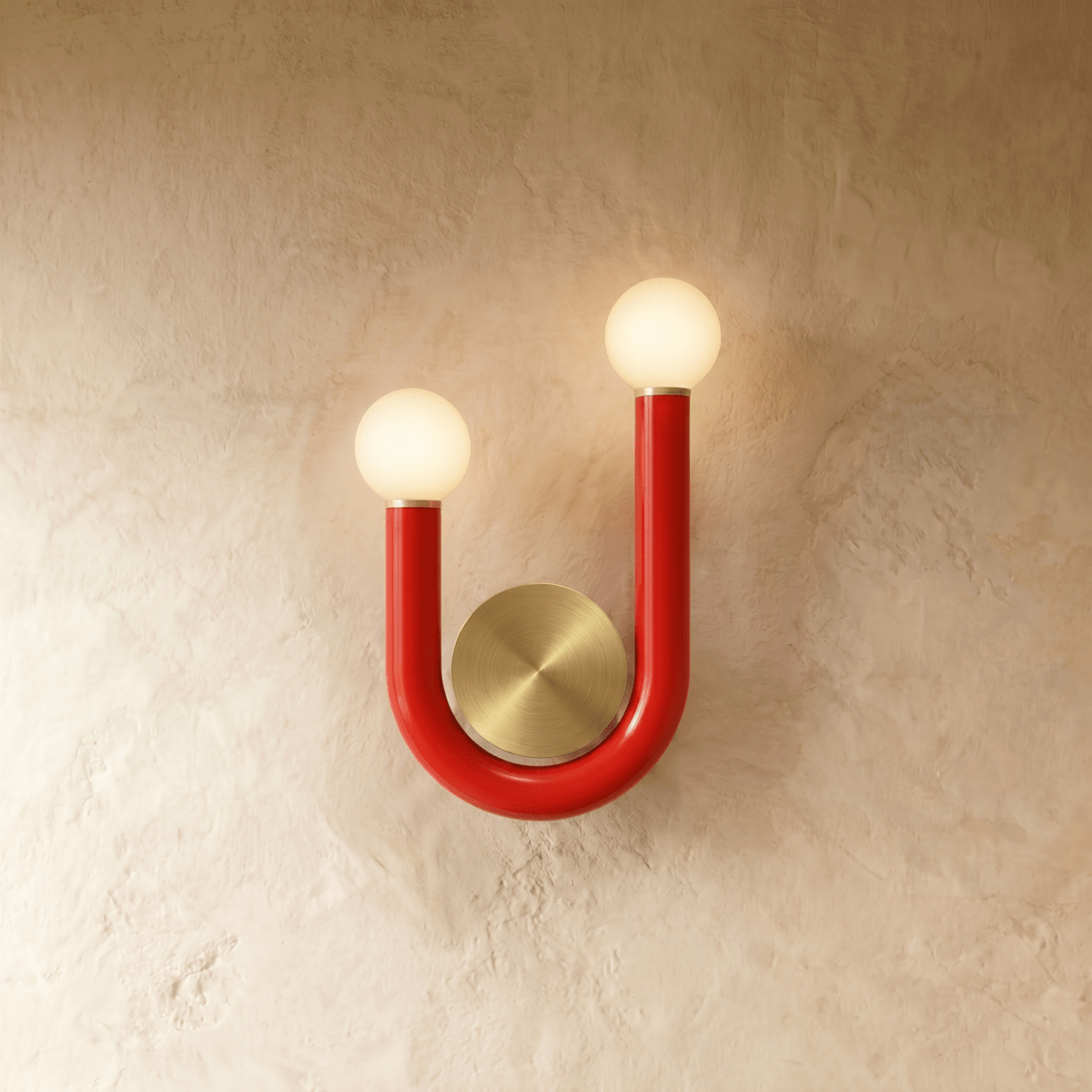 Clérachic U-shaped wall lamp in glossy red tube with two lit opal globes and a brushed brass backplate on a textured plaster wall.