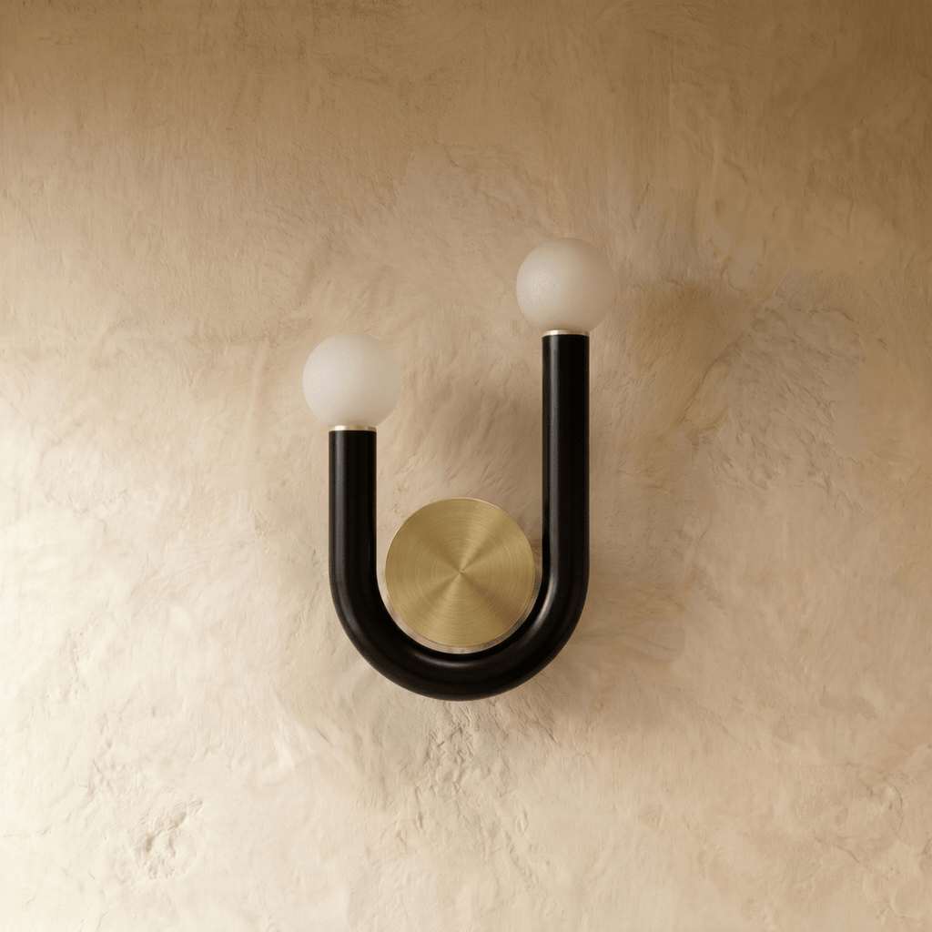 Clérachic black U-shaped wall lamp with two unlit frosted globes and brass collars, shown switched off against a plaster wall.